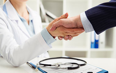 Woman doctor shaking hand with businessman in the office