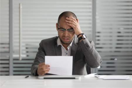 Man sitting at desk upset reading letter