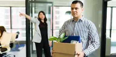 A man carrying possessions out of the office after being wrongully fired