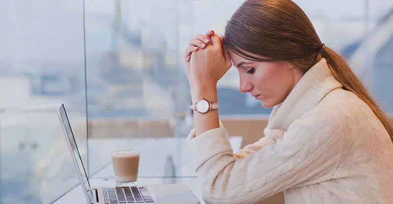 woman sitting at a desk with her computer thinking