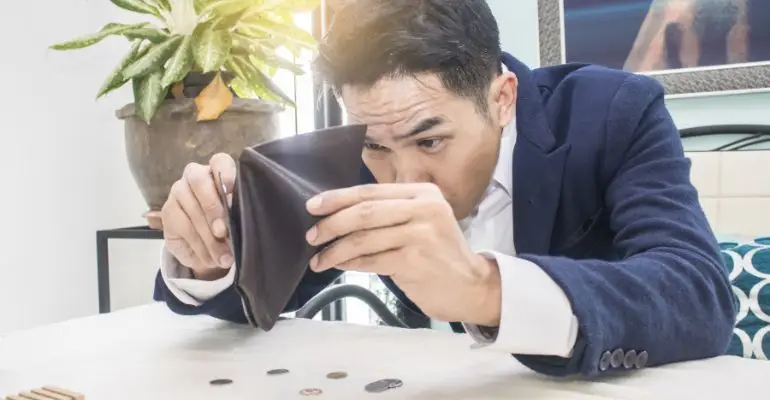 Person dumping out coins from a mostly empty wallet