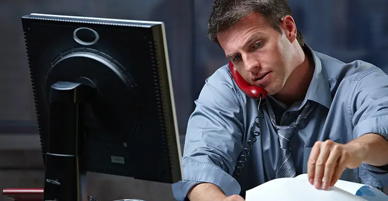 Man sitting at desk on the phone and looking through papers